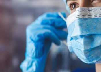 Profissional de saúde com máscara e luvas representa os médicos formados no exterior que aguardam o resultado da primeira etapa do Revalida 2026/1