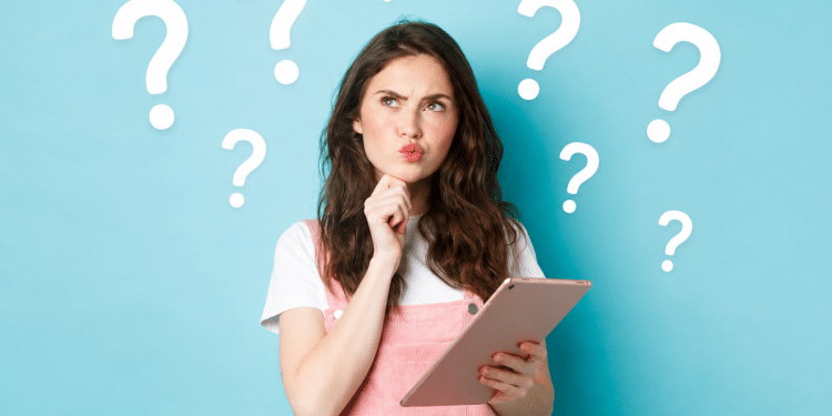 Jovem mulher com tablet faz expressão de dúvida diante de fundo azul com pontos de interrogação, simbolizando a dúvida entre checklist, check list e check-list.