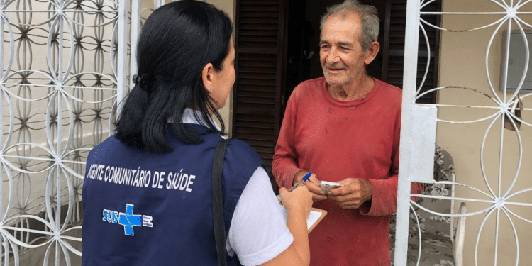 Agente comunitária do SUS realiza visita domiciliar e orienta morador.