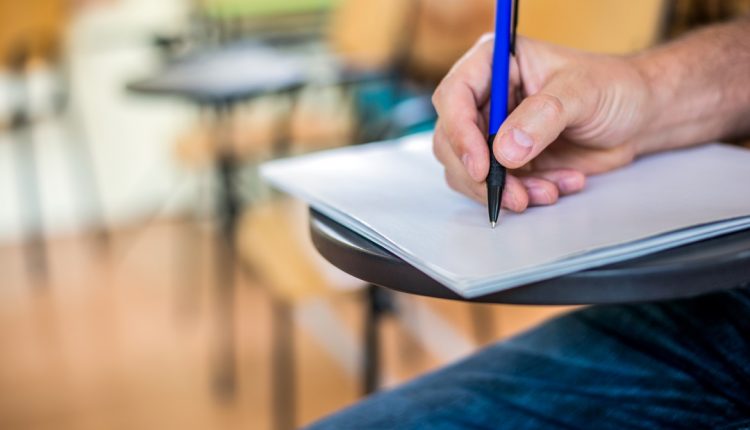 A man is writing/signing on a paper Focused on a hand with pen