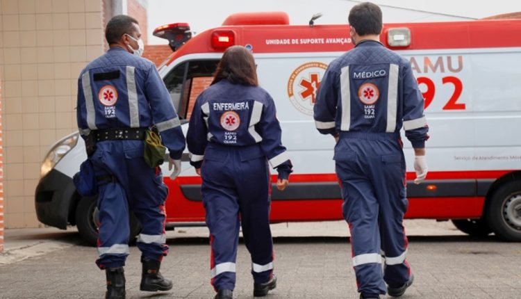 Profissionais do Samu de costas, andando em direção a ambulância