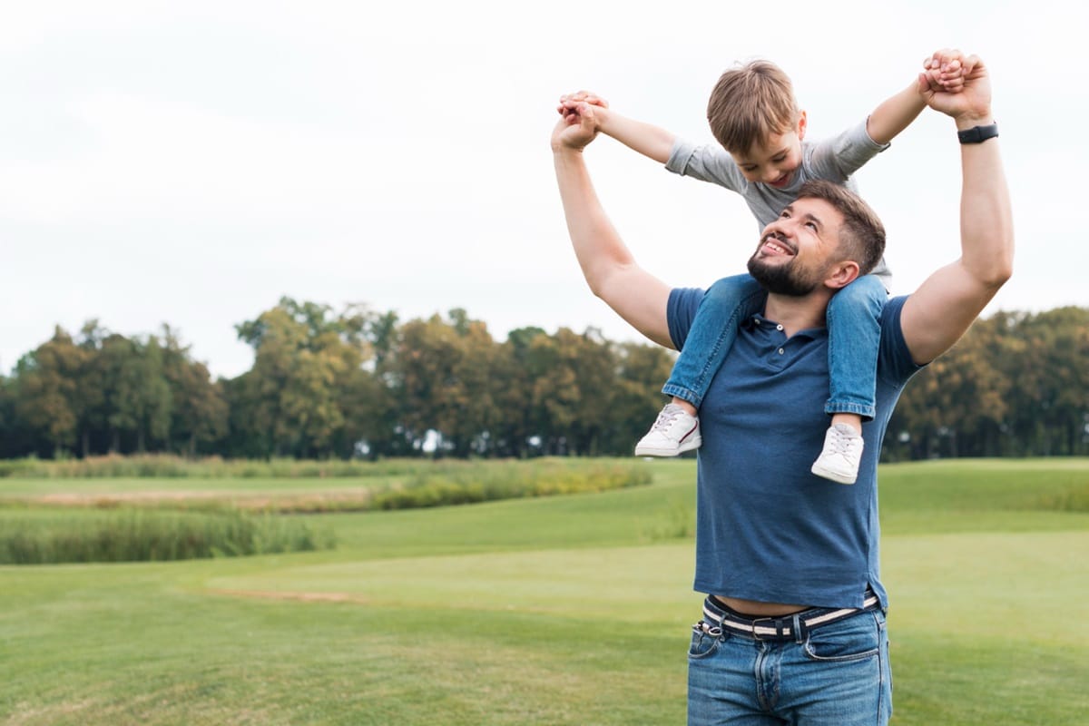 Pai e filho brincando ao ar livre, representando o vínculo paterno e a importância da paternidade na formação emocional da criança.