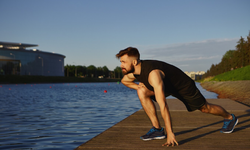 Homem se alongando antes de fazer exercício ao ar livre