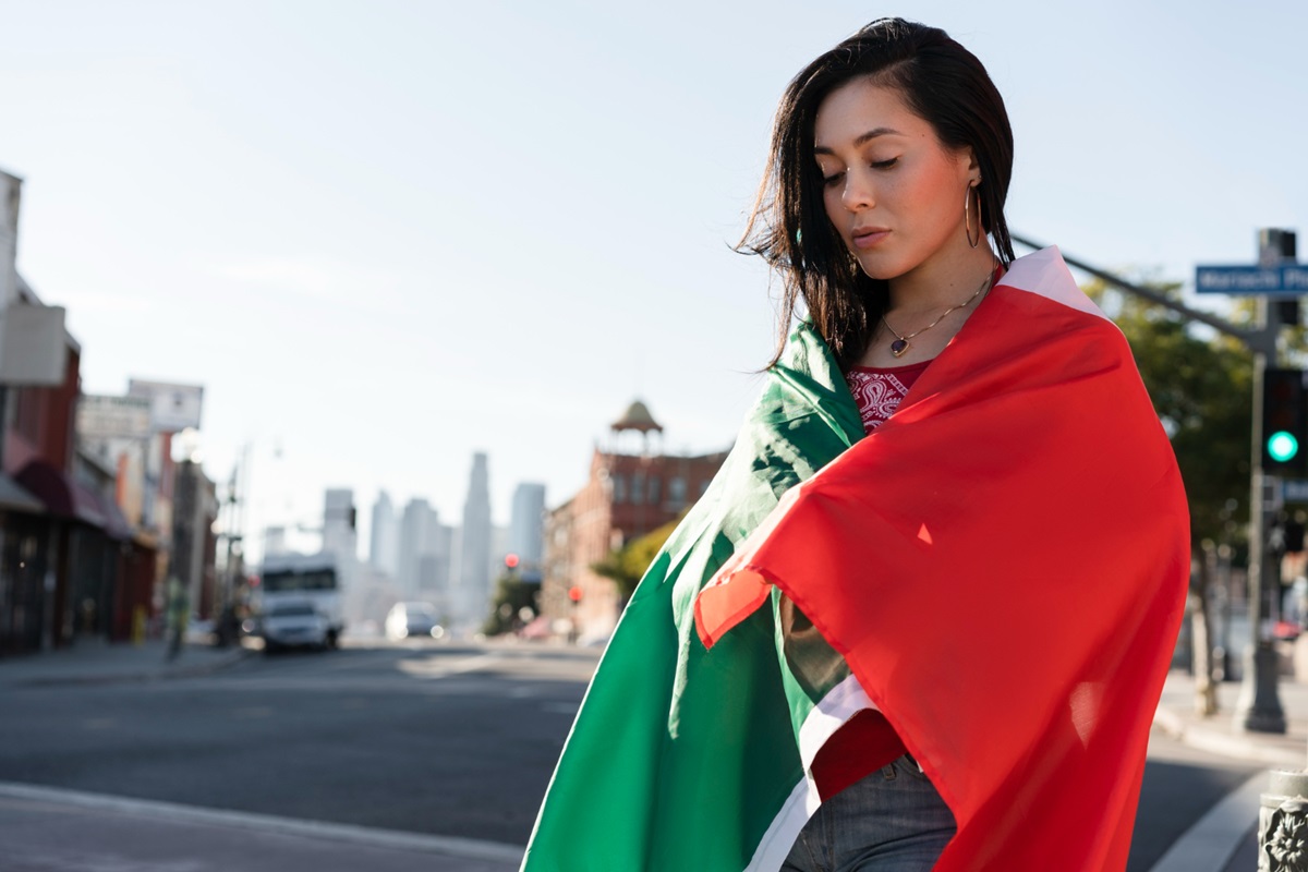 Mulher envolta na bandeira da Itália em uma rua urbana