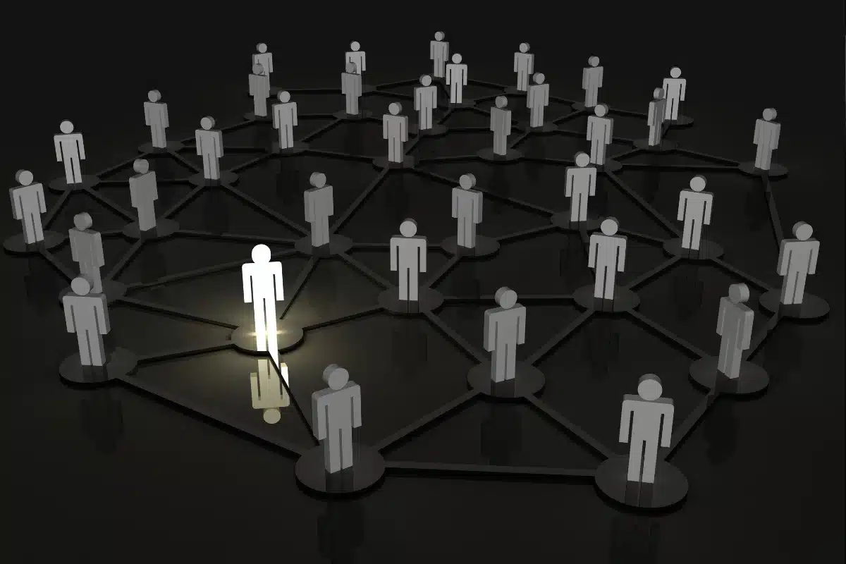 Pessoa destacada em uma rede de conexões, iluminada, enquanto as outras permanecem sombreadas.