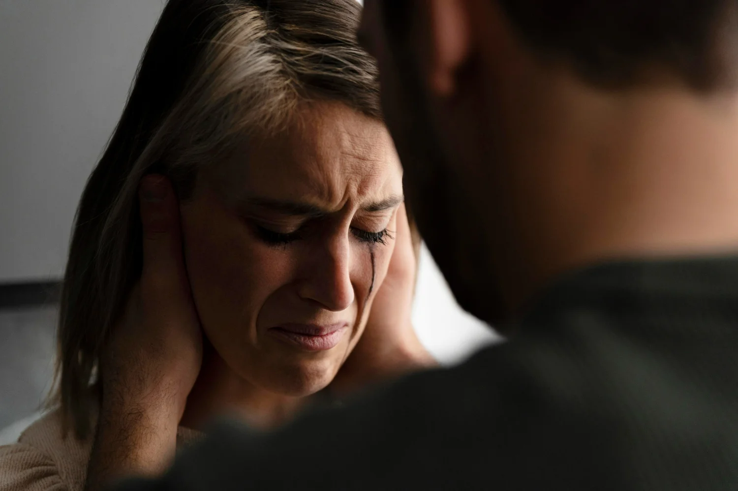 Mulher em sofrimento emocional, com o homem a pressionando, ilustrando uma situação de chantagem emocional.