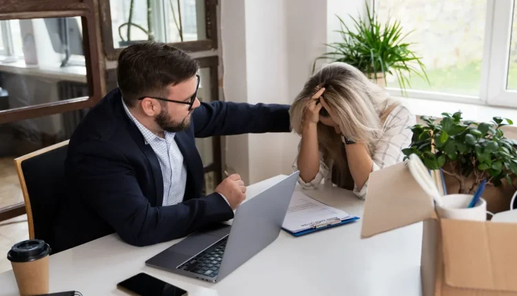 homem conforta colega de trabalho visivelmente abalada em ambiente corporativo