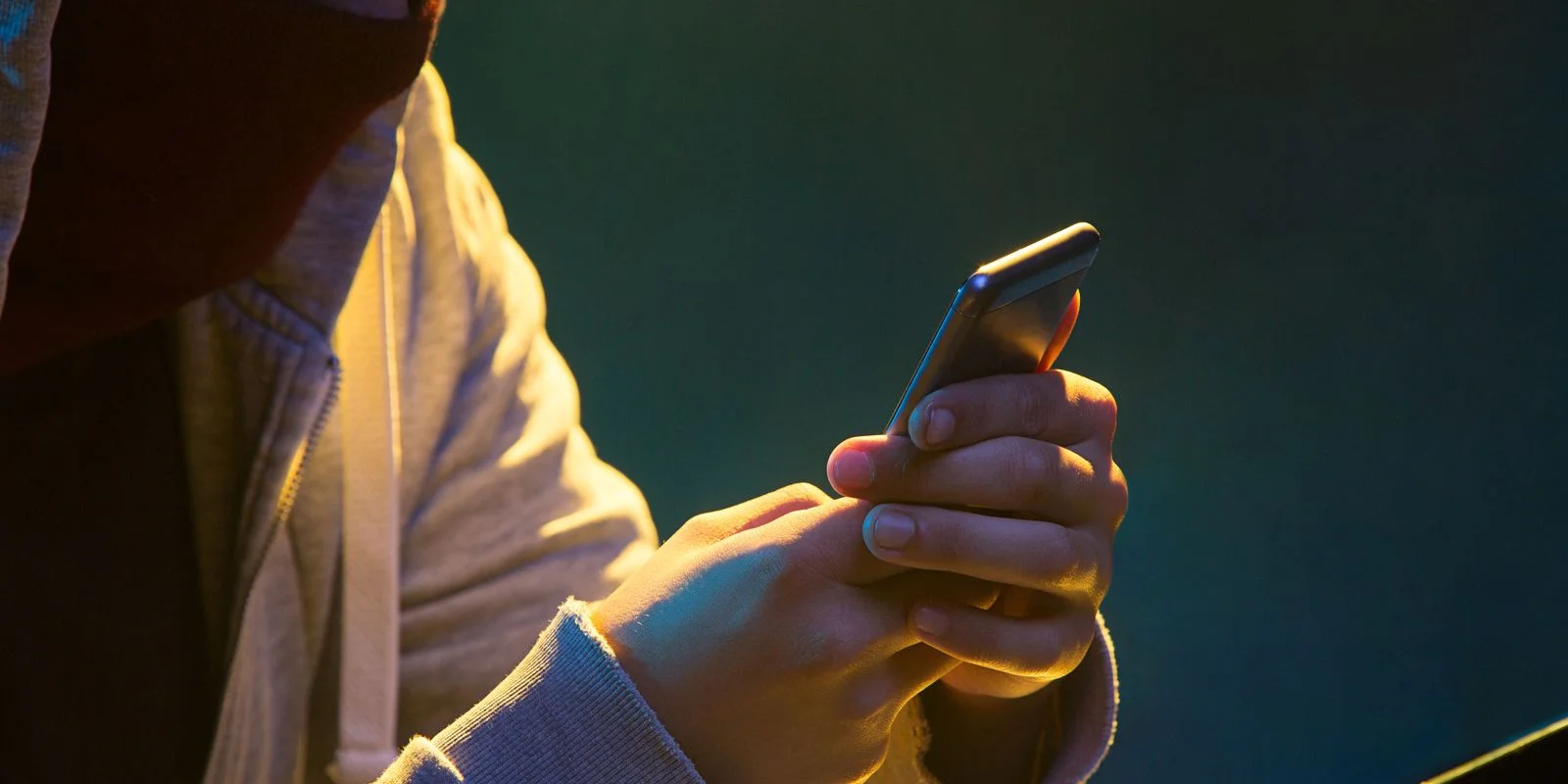 Pessoa com capô usando celular, representando a segurança de bloqueio no celular.
