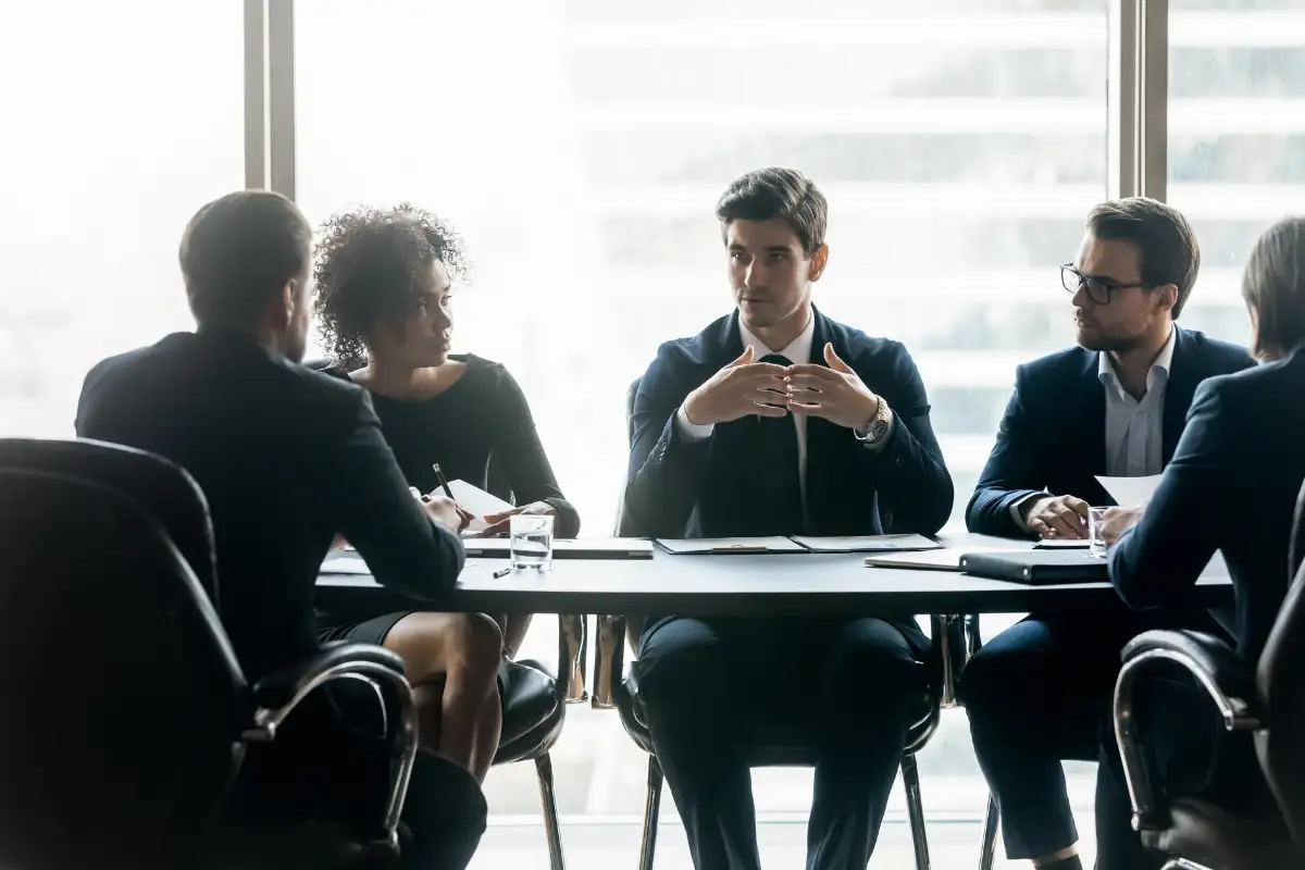 Reunião de equipe em ambiente corporativo com profissionais discutindo ideias em uma mesa.