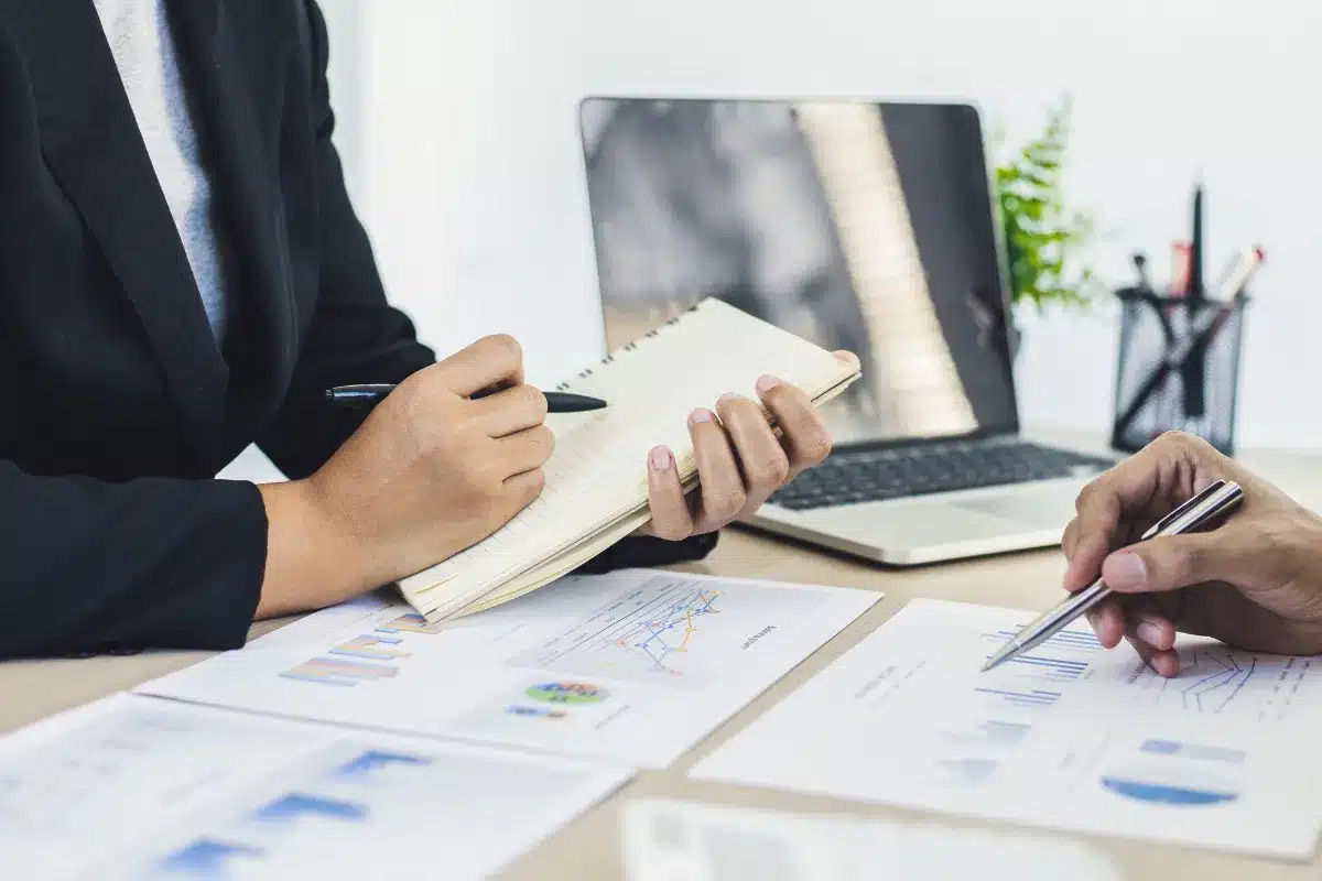 Profissionais analisando gráficos e dados em reunião de negócios, com foco em planejamento e estratégias.