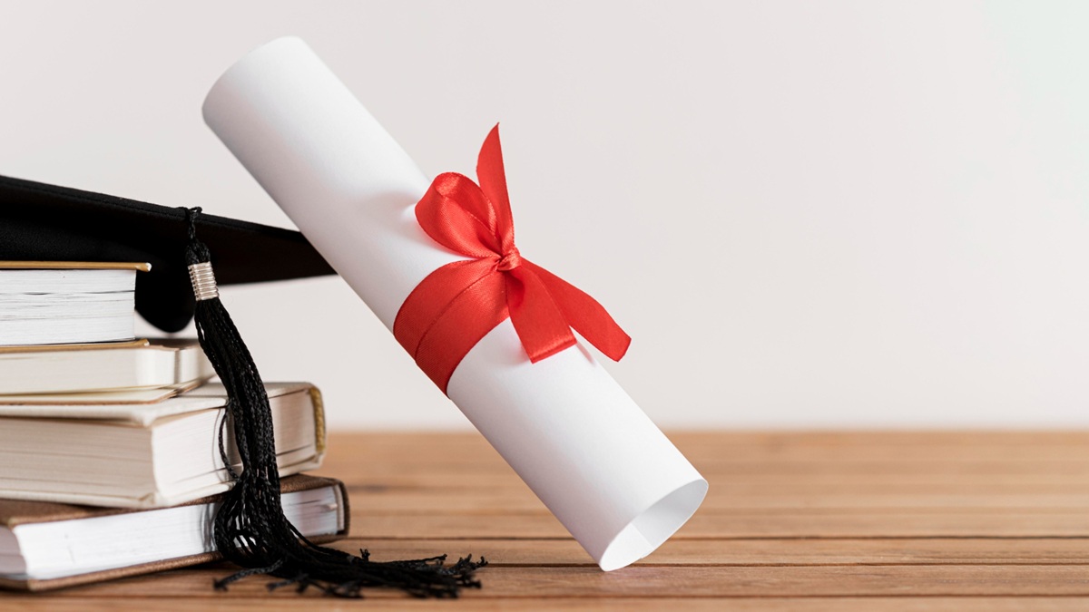 Rolos de diploma com fita vermelha e capelo ao lado, simbolizando formação em psicologia.