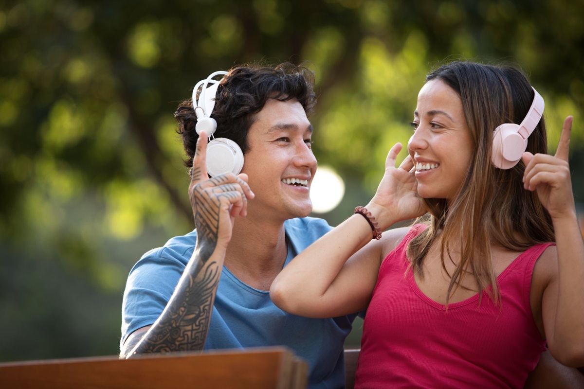 Casal feliz compartilhando música com fones de ouvido ao ar livre