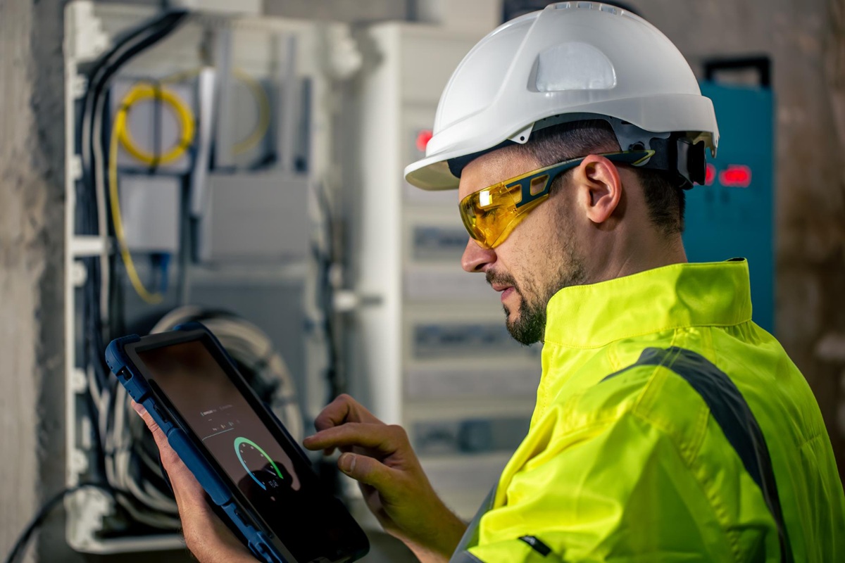 Técnico industrial com capacete usando tablet em ambiente de manutenção