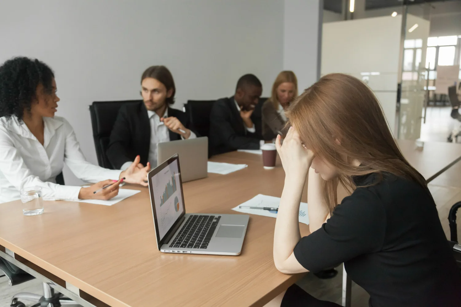 Mulher com expressão de frustração durante uma reunião de trabalho, demonstrando insegurança ao defender suas ideias.