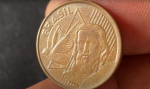 imagem em close de uma moeda de 5 centavos do brasil com figura masculina e uma pomba em destaque