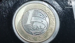 Moeda de 1 real do ano de 1998 sobre fundo preto, mostrando detalhes do anel dourado e centro prateado.