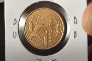 Moeda de 25 centavos de 2018 acondicionada em suporte de colecionador, representando peça com possível erro de cunhagem.