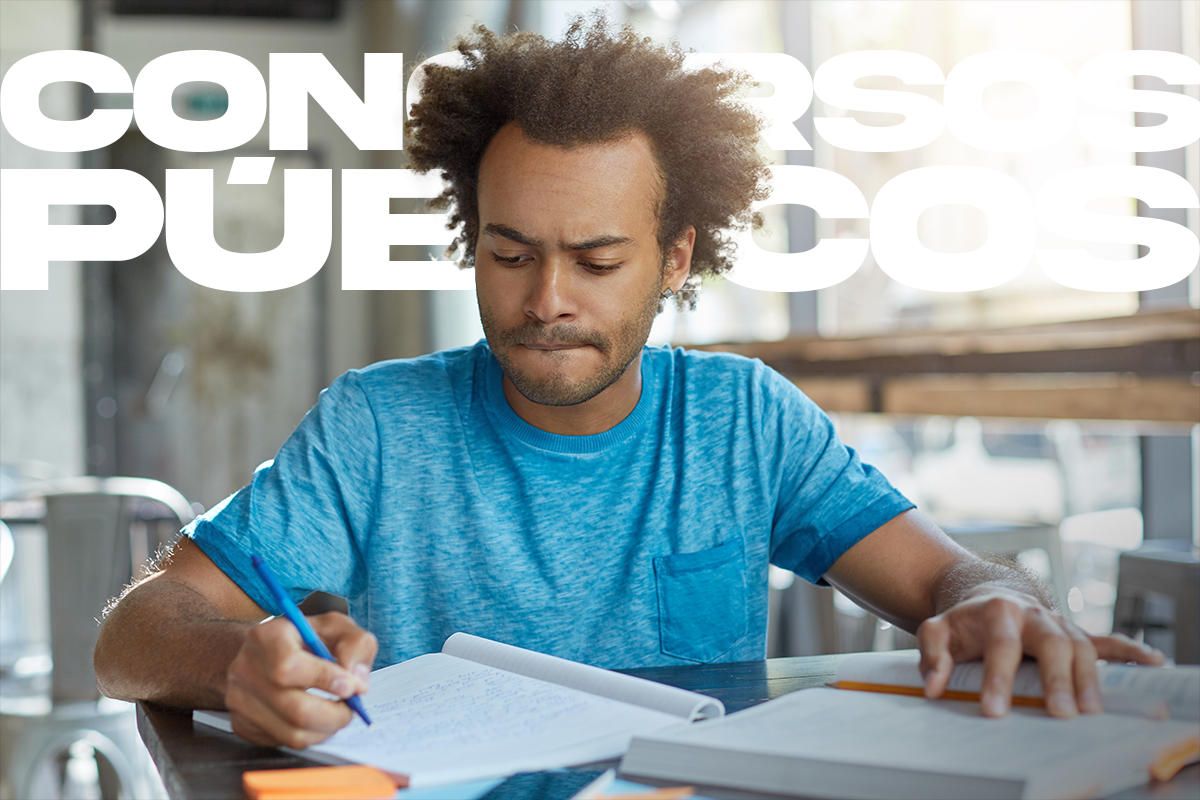 Jovem concentrado estudando em ambiente moderno com cadernos e livros abertos.