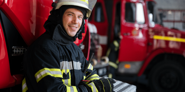 Bombeiro sorridente pronto para ação ao lado de caminhão de resgate.