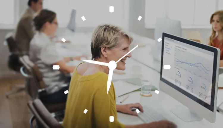Mulher sorrindo enquanto trabalha com gráficos e dados no computador, simbolizando produtividade no trabalho.