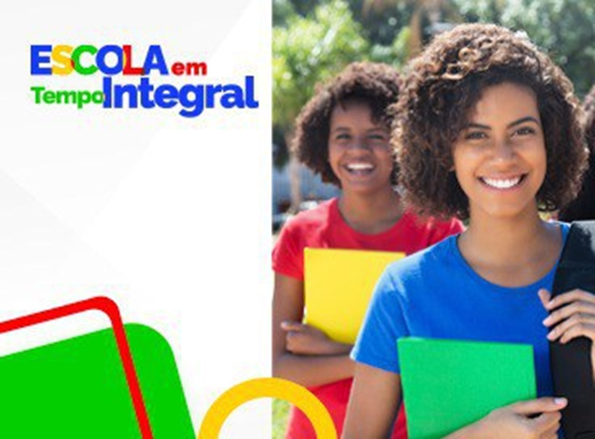 Duas estudantes sorridentes segurando cadernos coloridos ao ar livre.