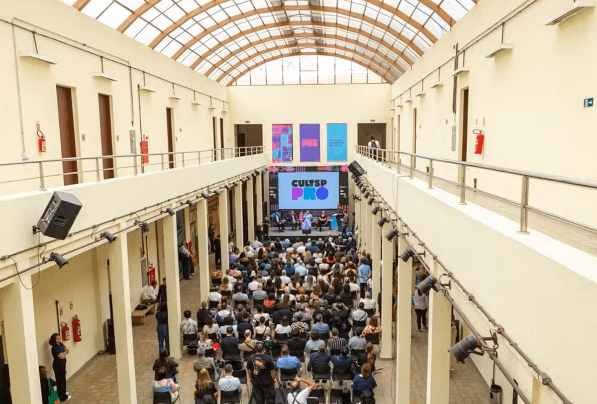 Auditório moderno com público assistindo a uma apresentação em evento educacional.