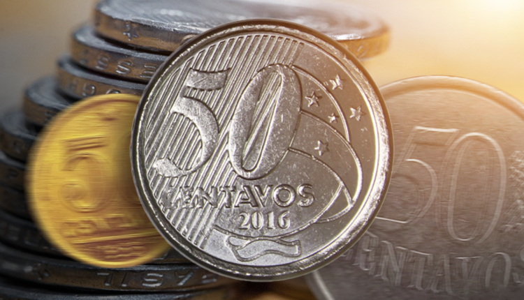 Moeda de 50 centavos de 2016 em destaque sobre fundo com outras moedas brasileiras