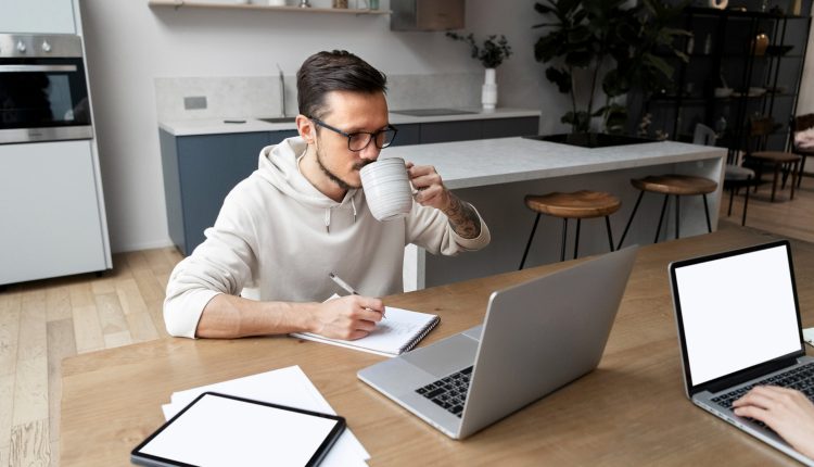 Pessoa tomando café enquanto trabalha remotamente em sua casa.