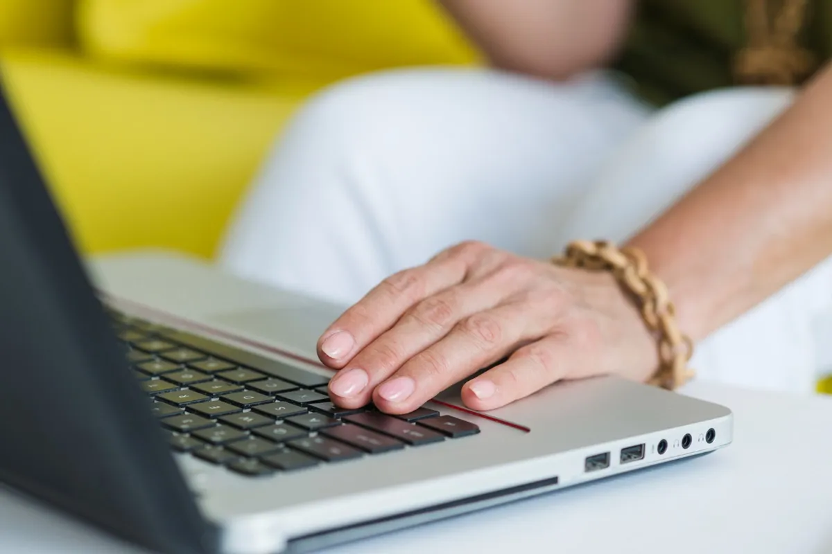 Mão digitando em teclado de laptop moderno