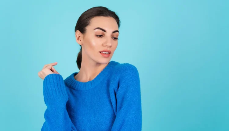 Mulher com suéter azul olhando para o lado em fundo azul claro, representando a preferência pela cor azul
