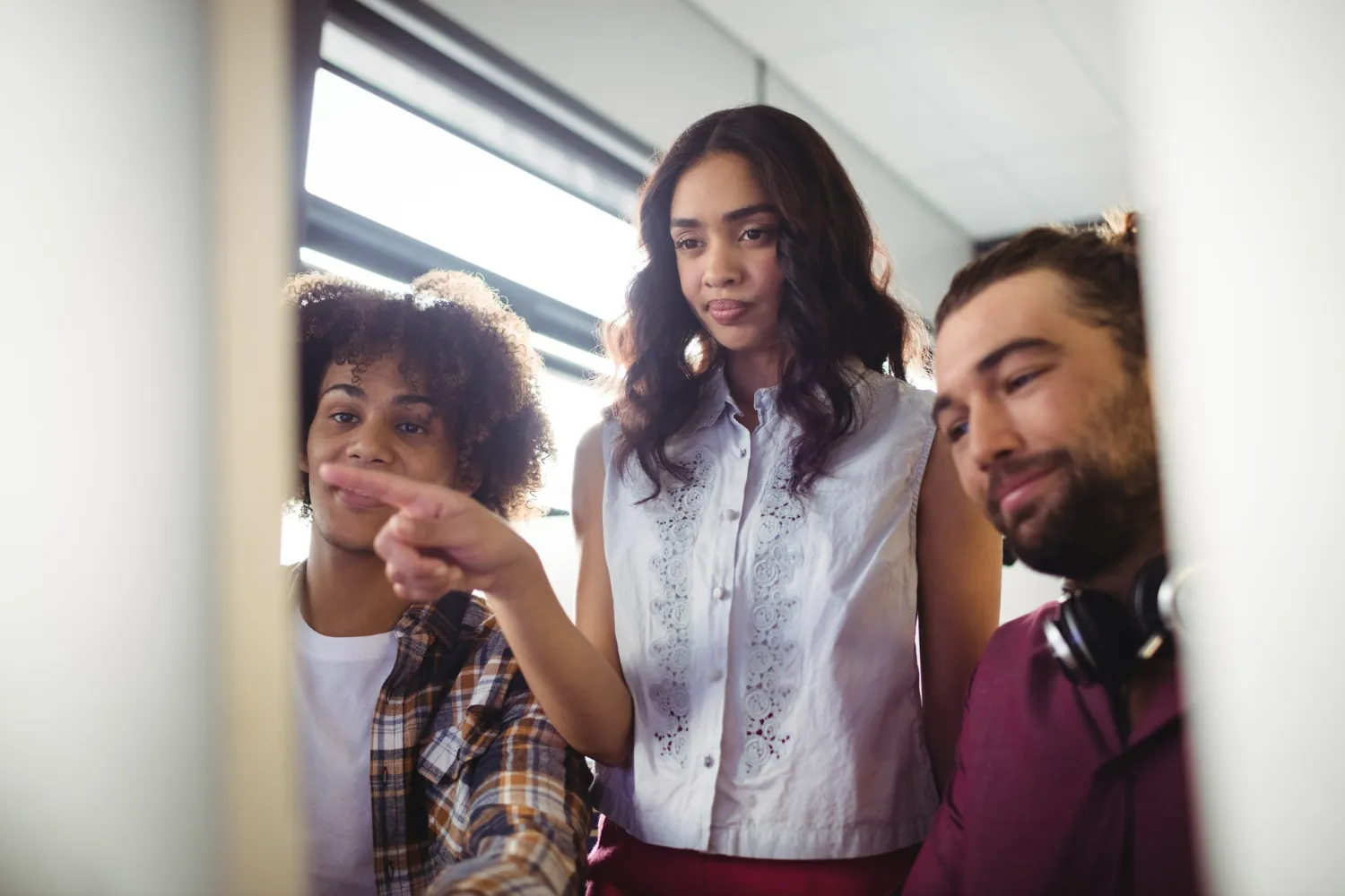 Grupo de colegas analisando algo na tela do computador em ambiente de trabalho.