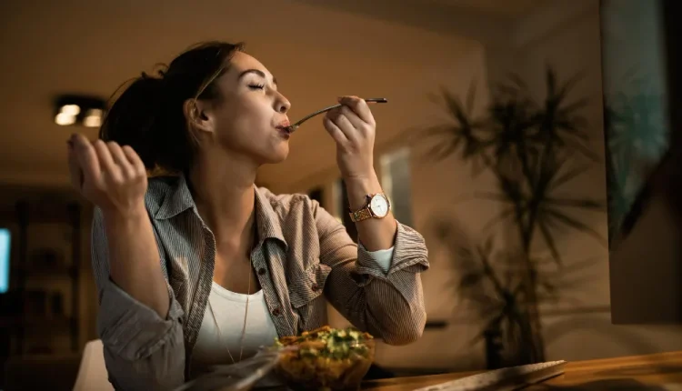 Mulher apreciando sua refeição enquanto trabalha, mostrando como a comida pode ser um momento de relaxamento e alívio do estresse