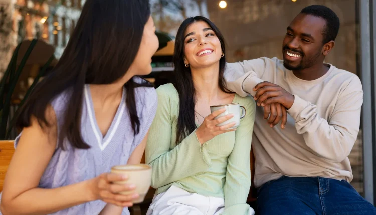 Três pessoas sorrindo e se conectando em uma conversa amigável com xícaras de café, ilustrando a ideia de criar conexões fortes por meio da comunicação empática.