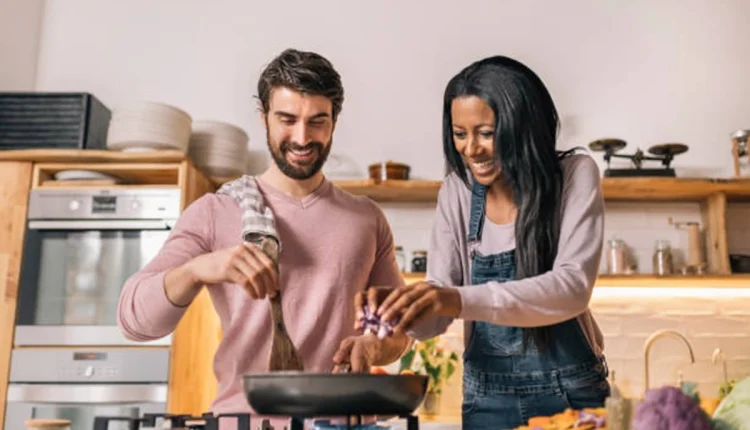 Casal feliz preparando comida juntos na cozinha moderna