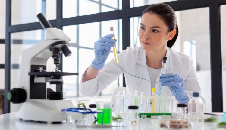 Técnica de laboratório analisando amostras químicas em tubos de ensaio em ambiente científico moderno