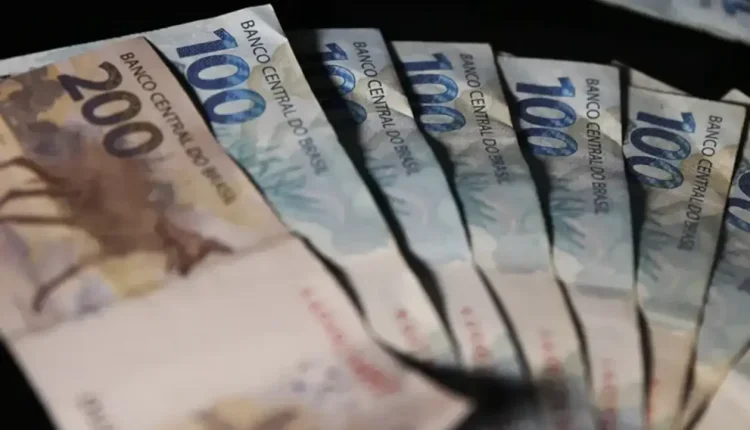 Notas de R$ 100 e R$ 200 do Banco Central do Brasil em foco, com destaque para a cédula de R$ 100.