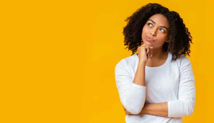 Mulher pensativa com fundo amarelo, refletindo sobre o plural da palavra 'gravidez'.