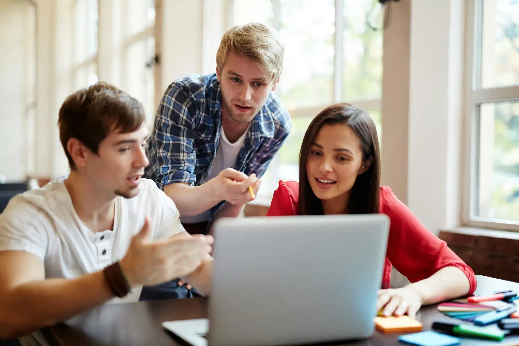 Grupo de jovens profissionais colaborando em projeto usando notebook.