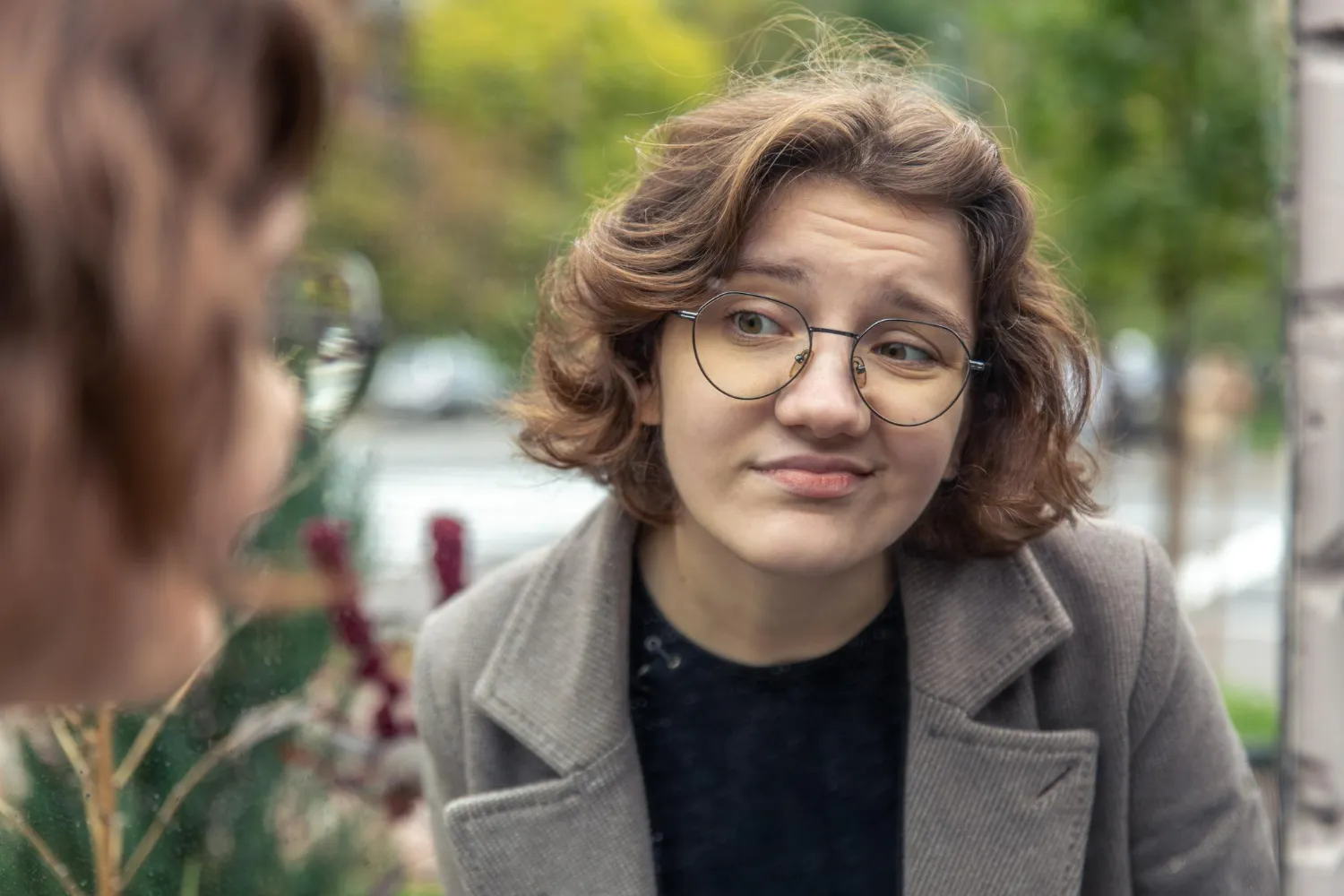 Mulher olhando com uma expressão desconfortável, sugerindo evasão ou desonestidade, enquanto observa seu reflexo em uma superfície, talvez tentando esconder algo.
