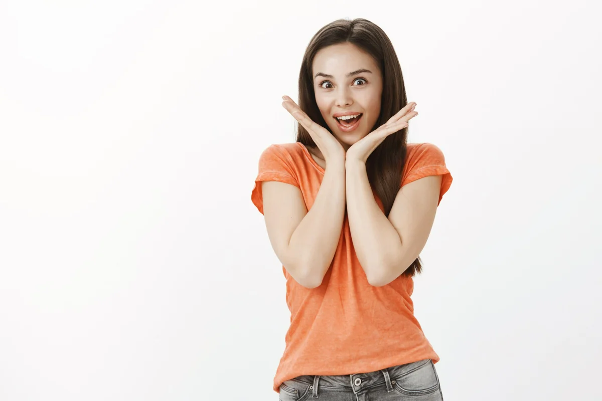 Mulher surpresa com as mãos ao redor do rosto, expressando espanto.