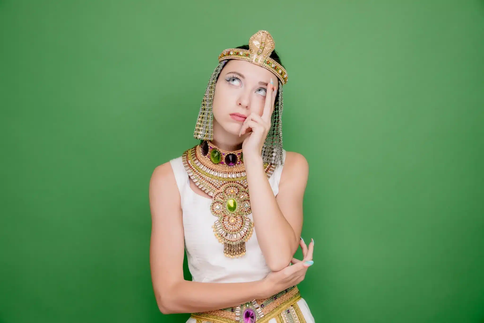 Mulher vestida com traje egípcio antigo, com expressão pensativa, imitando a aparência de Cleópatra.
