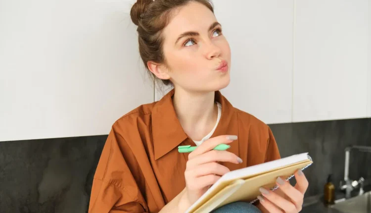 Pessoa pensando enquanto escreve em um caderno, com destaque para a dúvida sobre o uso de acento em 'início' e 'inicio