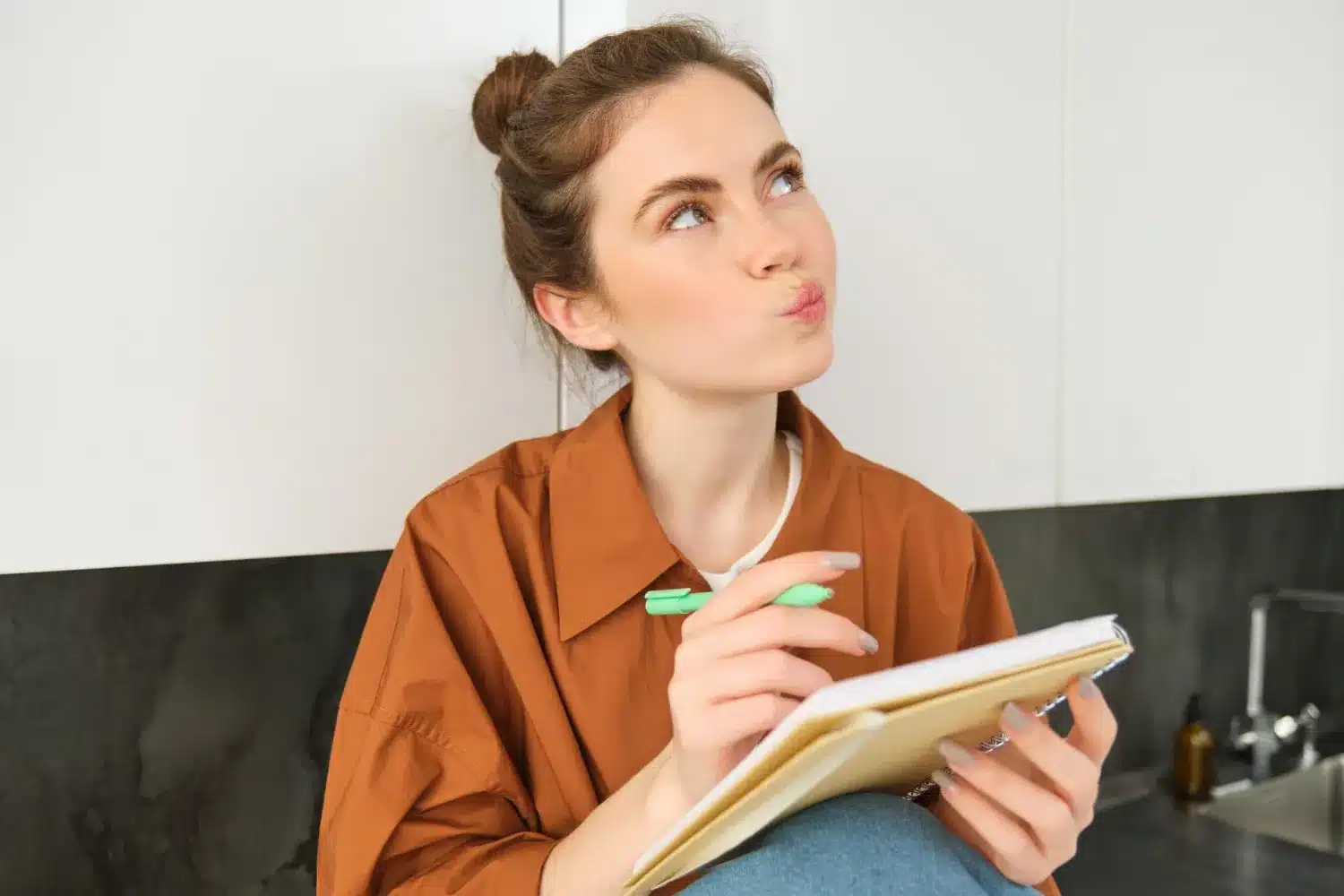 Pessoa pensando enquanto escreve em um caderno, com destaque para a dúvida sobre o uso de acento em 'início' e 'inicio