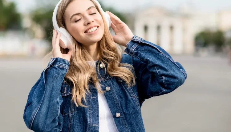 Jovem sorrindo com fones de ouvido, curtindo música ao ar livre