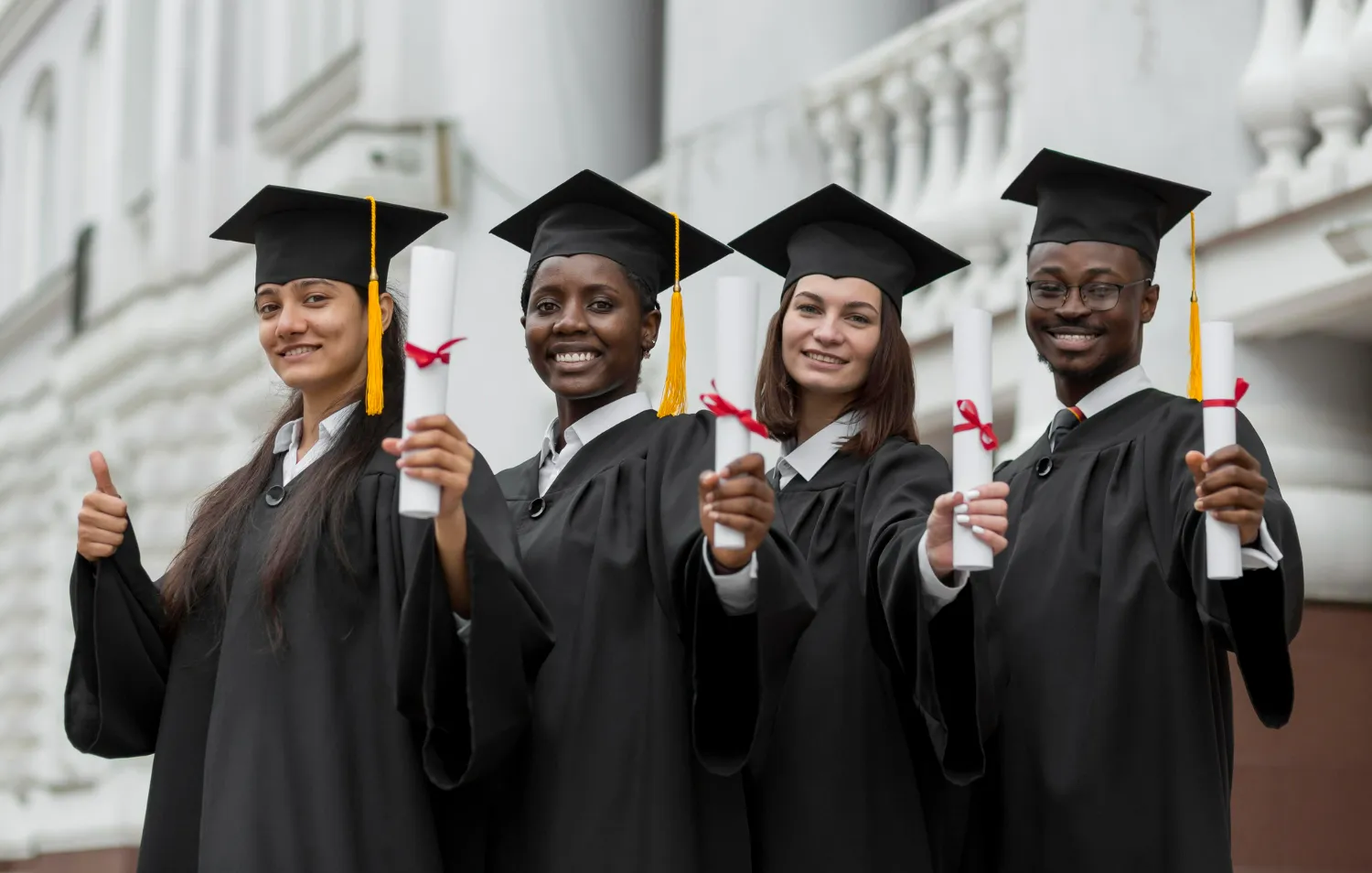 Grupo diversificado de estudantes universitários sorrindo e segurando diplomas após a formatura.Título: Estudantes comemorando a formatura na universidade.