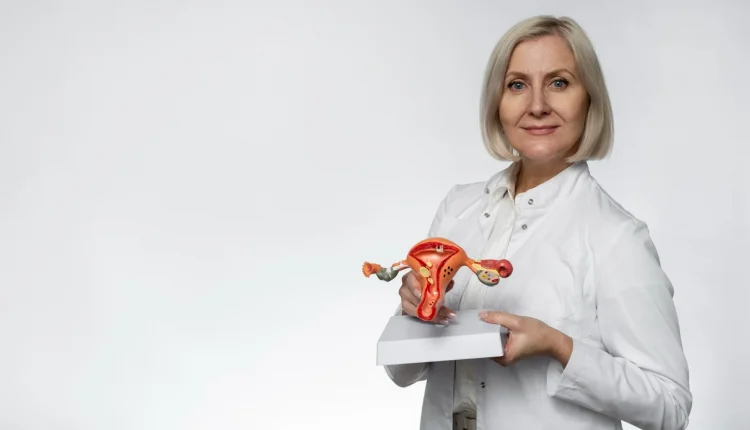 Médica com modelo anatômico do sistema reprodutor feminino, ilustrando um tema sobre laqueadura e vasectomia.