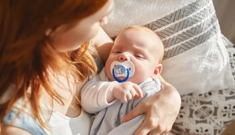 Mãe segurando carinhosamente seu bebê reborn com chupeta azul