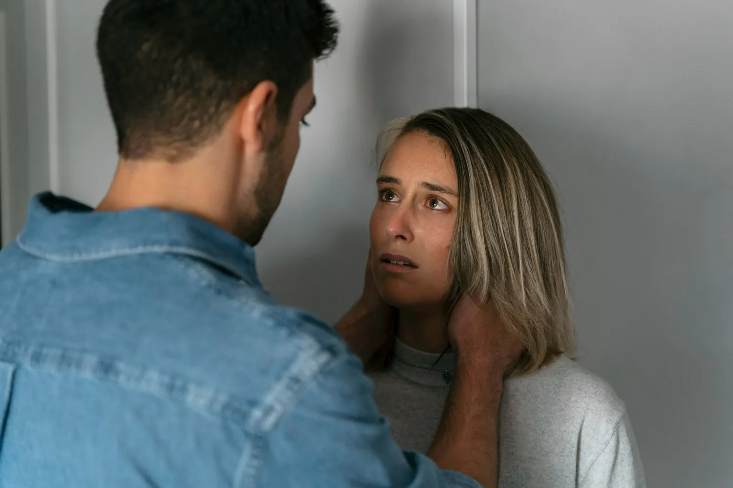 Homem segurando o rosto de uma mulher com expressão preocupada, simbolizando manipulação emocional.