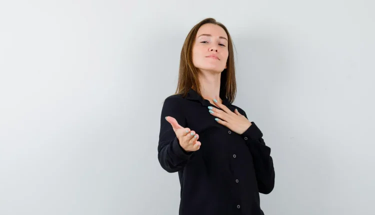 Mulher com expressão confiante e mão no peito, simbolizando comportamento egocêntrico.