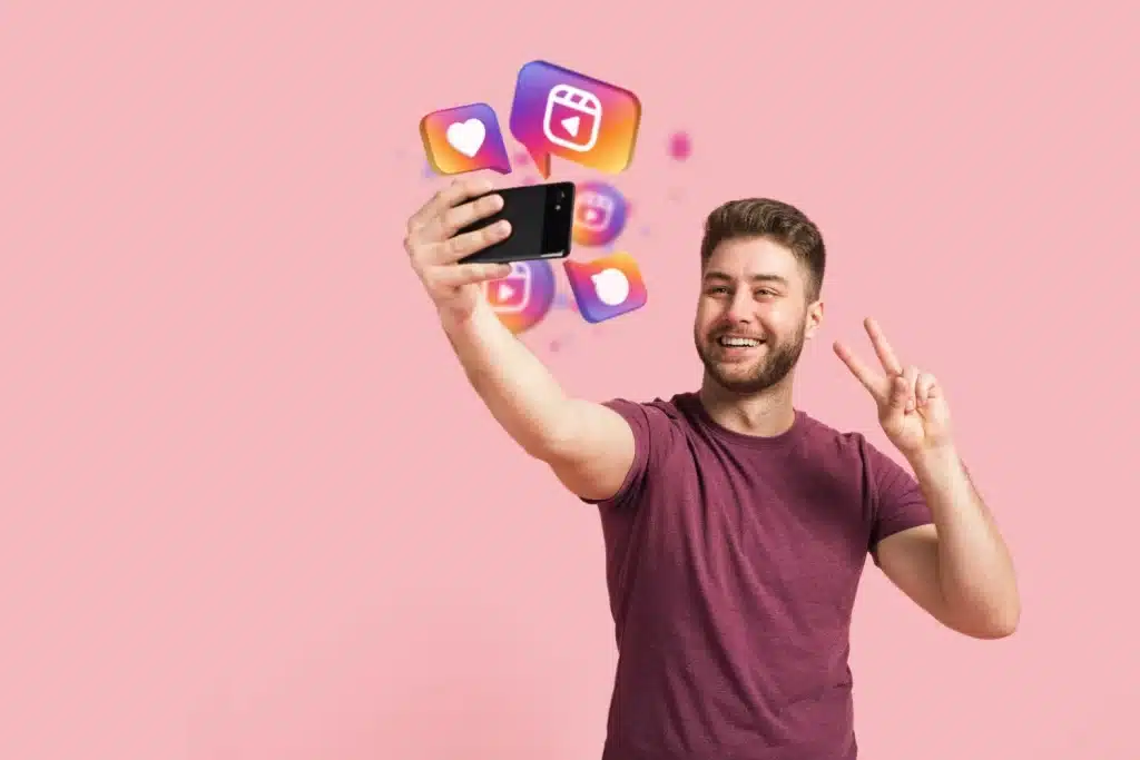 Escolha entre WhatsApp e Instagram reflete sua personalidade digital Homem sorridente tirando selfie com ícones do Instagram flutuando ao redor do celular, simbolizando a preferência por redes sociais